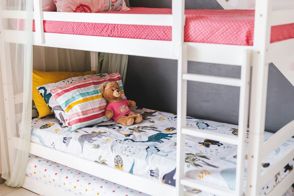 A child's bed, made, in a bedroom before school